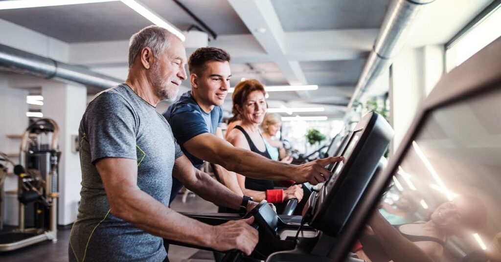 Young man helping the older man with his treadmill