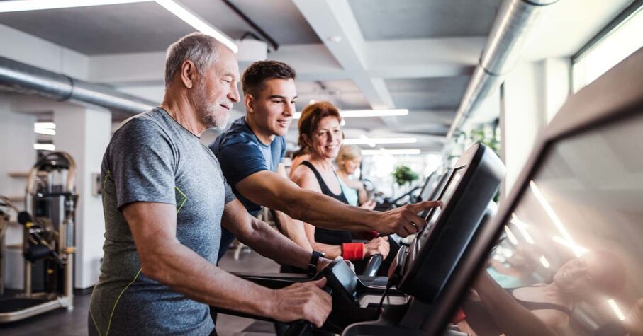 Young man helping the older man with his treadmill