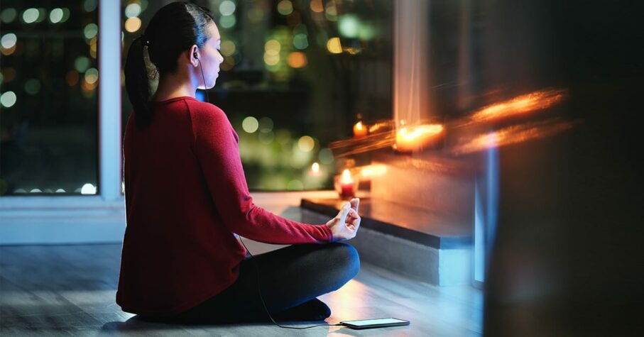 woman meditating at night with candles using mental health apps