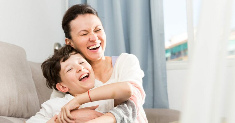 single mother with her son on the sofa laughing