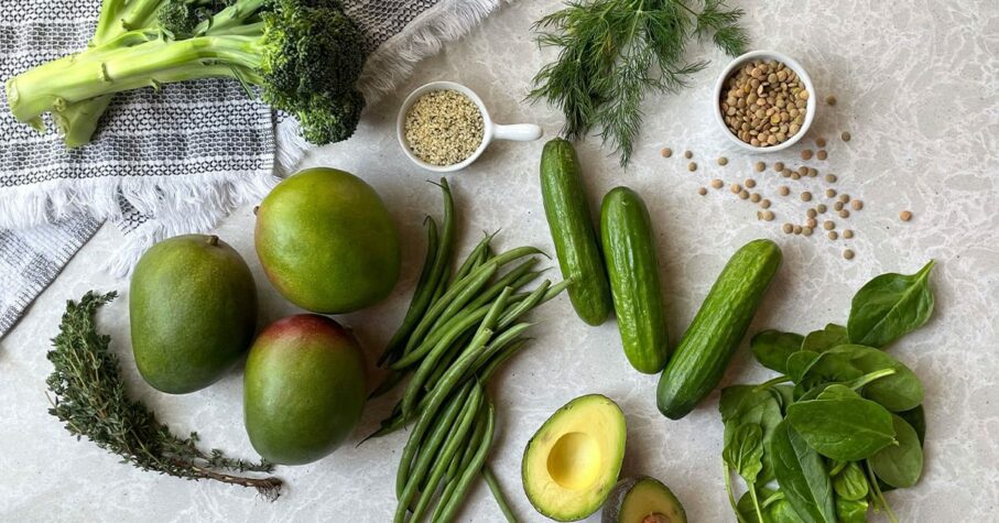 Different green fruits and vegetables on top of the table