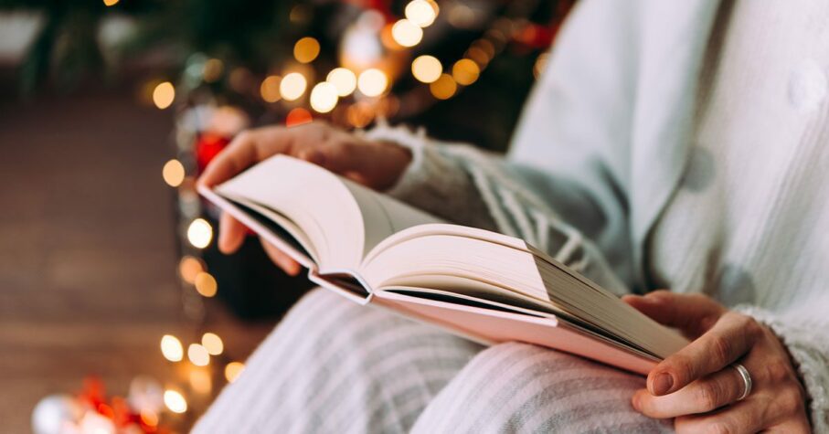 Person in pyjamas reading a book during the Holiday to manage holiday stress