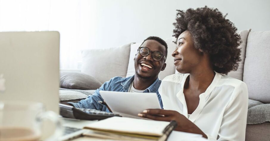 Young married couple doing their paperwork together, paying bills online. Focus on the guy. Loving young couple using laptop and analyzing their finances.