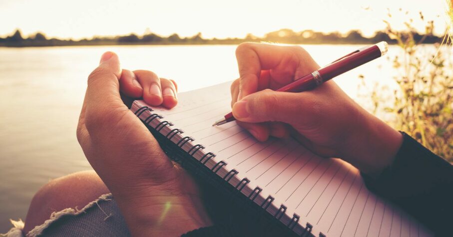 close up hand of young woman with pen writing a journal