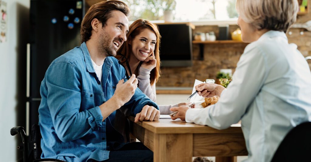 A couple with a man on a wheelchair discussing with an advisor to check his eligibility for life insurance