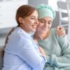 woman hugging a female friend with ovarian cancer in the couch.